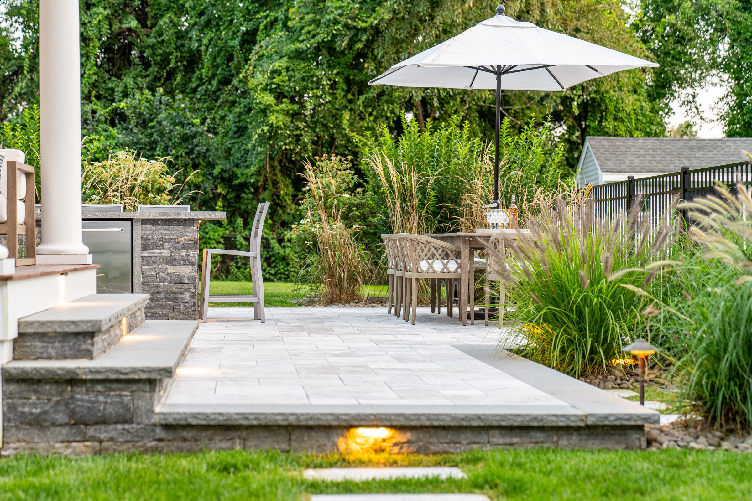 Stone paver dining patio with outdoor kitchen. Dex by Terra Landscape design / build project in Andover, Massachusetts.