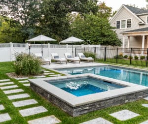 Poolside spa with stone veneer and granite cap in Andover, Massachusetts. Masonry designed and built by Dex by Terra.