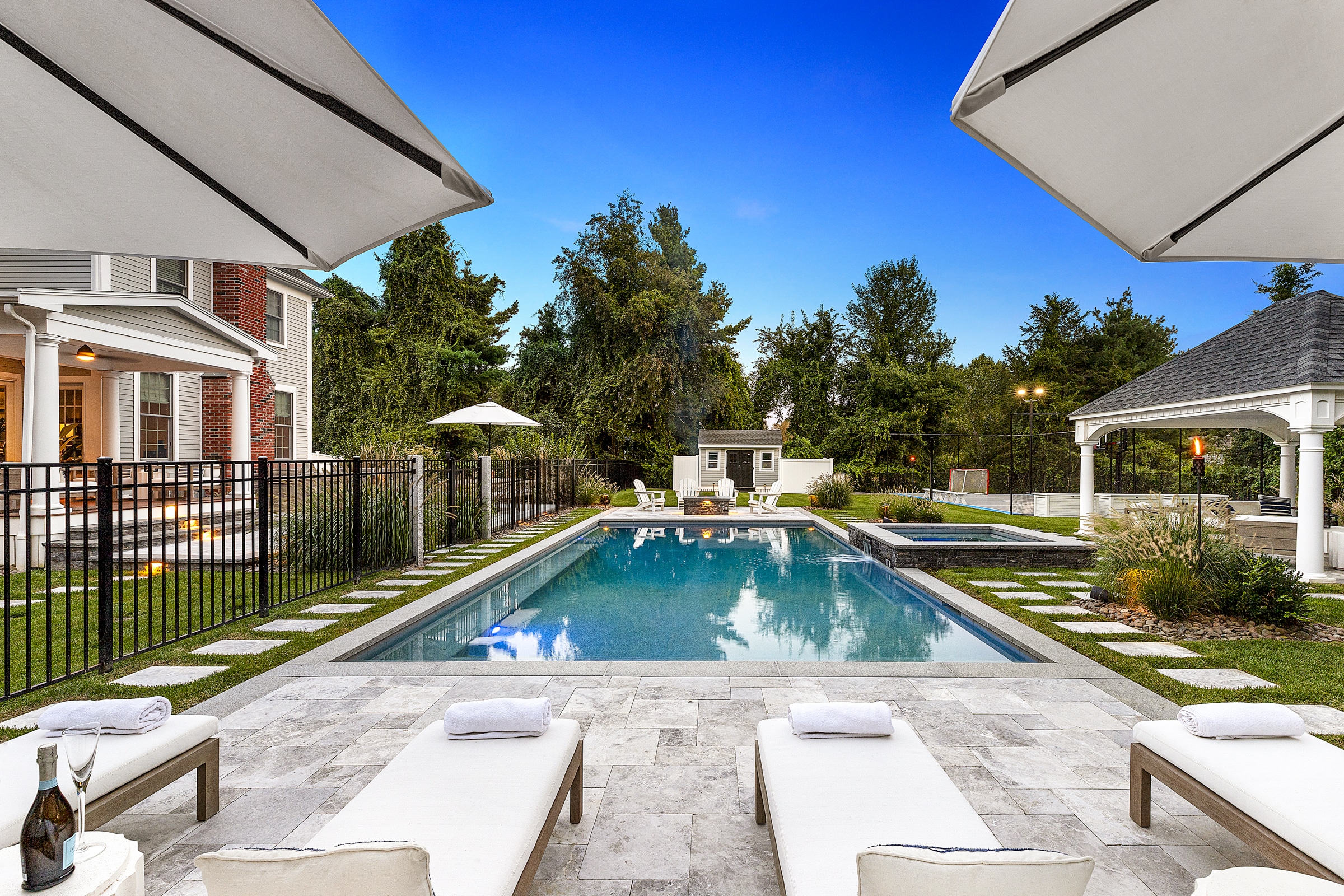 Stone paver pool deck with sun chairs. Dex by Terra Landscape design / build project in Andover, Massachusetts.