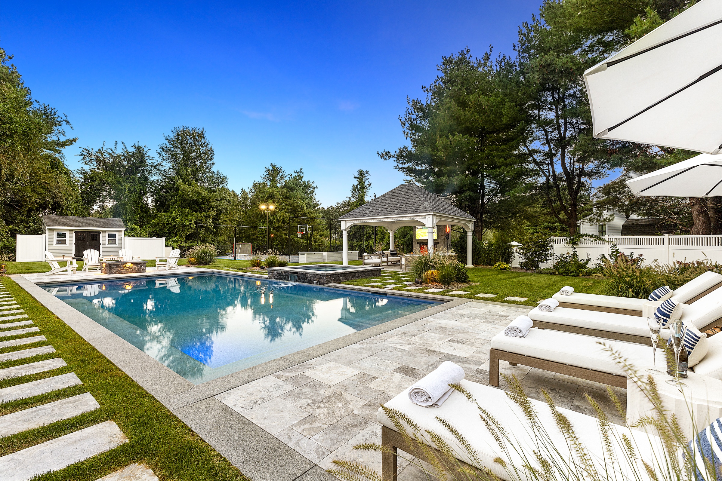 Stone paver pool deck with attached spa and Gazebo in Andover, Massachusetts. Dex by Terra Landscape design / build project.