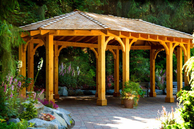 A beautifully crafted wooden pavilion in Massachusetts, featuring natural wood, a shingled roof, and a serene, landscaped garden setting.